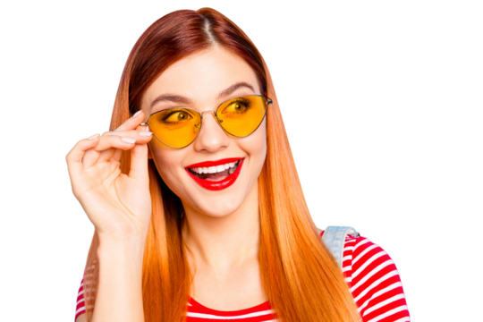 Attractive young girl with red hair looks on side with surprised face and hold glasses by hand isolated on bright blue background