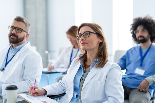 Group of doctors on conference, medical team sitting and listening speaker. Medical experts attending an education event, seminar in board room.