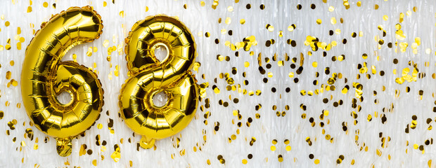 Golden foil balloon number, figure sixty-eight on white with confetti background. 68th birthday...