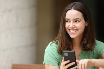 Happy woman looking at side holding phone