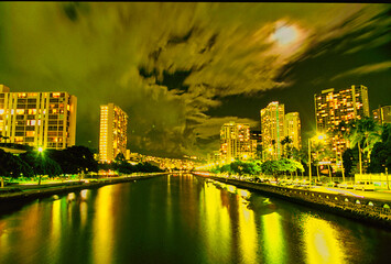 View of Ala Wai Canal in Waikiki with a full moon at night - obrazy, fototapety, plakaty