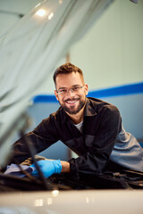 A mechanic man is working in his garage while smiling for the camera. - 761357971