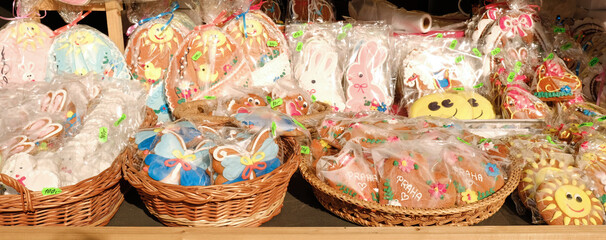 Traditional Easter gingerbread cookies in the shape of a colorful egg with drawings of a hare and chickens are sold at a market