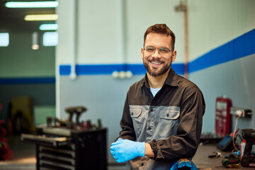 A smiling mechanic technician working at his car repair service, posing for the camera. - 761358552