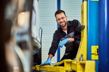 A smiling mechanic looking at the camera while working at the car repair service. - 761358951