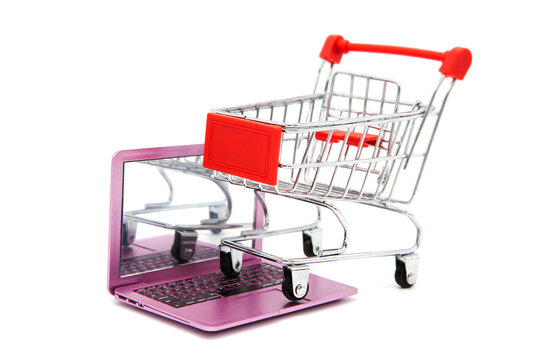 Shopping supermarket cart stands on an open laptop isolated on a white background. Online shopping.	