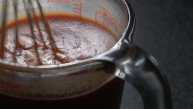 Stirring enchilada sauce in glass measure jar