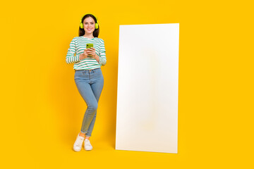 Full size photo of cute casual wear charming girl chatting phone promote ad isolated on yellow...