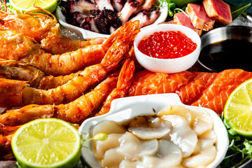 Assortment of seafood including grilled shrimp, fresh salmon sashimi, and cooked scallops,...