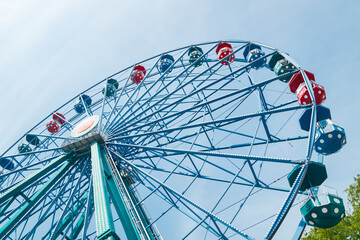 Colorful ride ferris wheel in motion in amusement park on sky background.