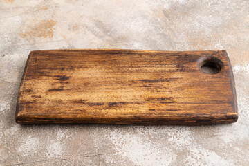 Empty rectangular wooden cutting board on brown concrete. Side view