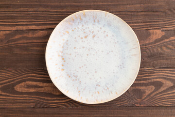 Empty blue and gold ceramic plate on brown wooden. Top view, copy space