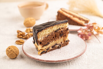 Chocolate biscuit cake with caramel cream and walnuts on gray concrete. side view, selective focus