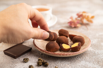 Japanese rice chocolate mochi filled with cream with hand on brown concrete. side view, selective focus.