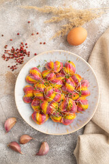 Rainbow colored dumplings with microgreen on brown concrete. Top view, flat lay.