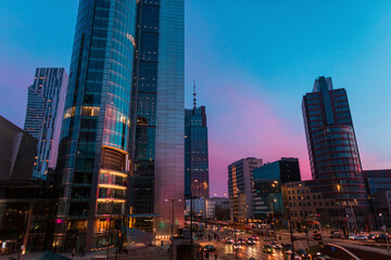 Fototapeta na wymiar Beautiful modern city of Warsaw with buildings and road on the evening sunset sky with blue and pink light. Poland