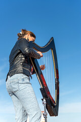 Harpist with electronic harp studying on the roof