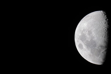 High resolution half moon photo on a uniform black background, which is ideal for use as a presentation slide template.  The moon is located in the middle right to facilitate copy space for text.