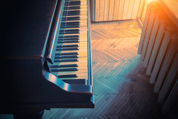 An old piano in the room near the window. Vintage grand piano in the evening light.