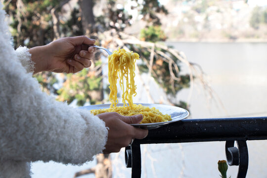 A child eating noodles in front of a lake.its a focus image.
