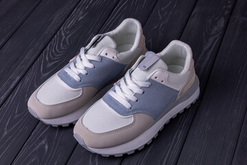 Light female sneakers on a wooden background