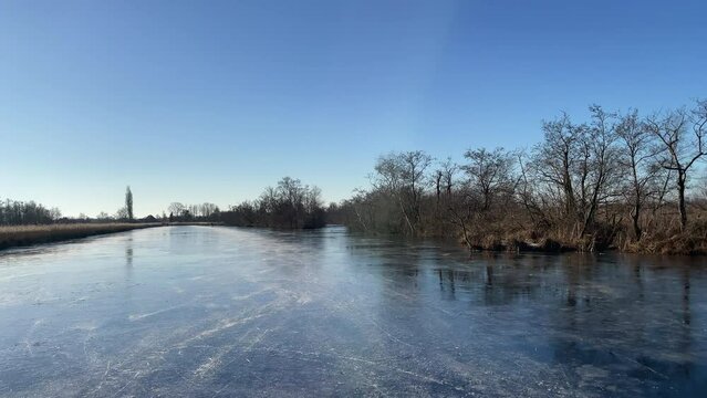 Ice skating on a frozen lake in the Weerribben Wieden nature reserve during a cold winter day in The Netherlands.