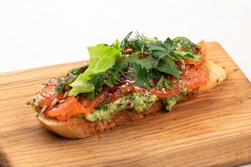 Breakfast toast with salmon and avocado on wooden board