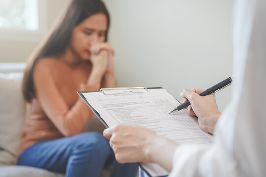 Psychology, depression. Sad, suffering asian young woman, girl consulting with psychologist, psychiatrist while patient counseling mental with doctor hand taking notes at clinic. Encouraging, therapy.