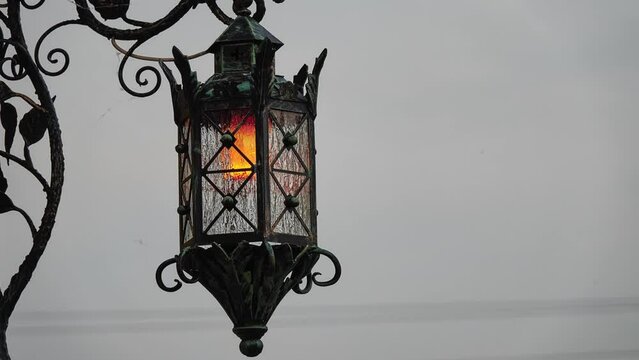 Beautiful forged lantern with stained glass on the wall of the house.