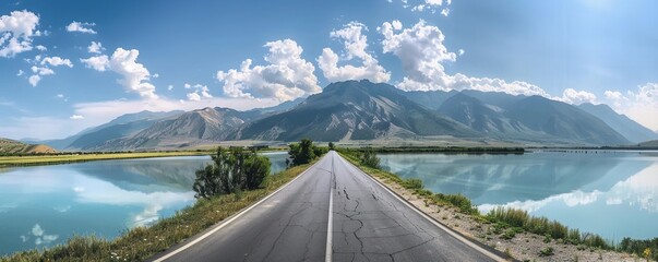 Countryside roadway between mountains and calm lake