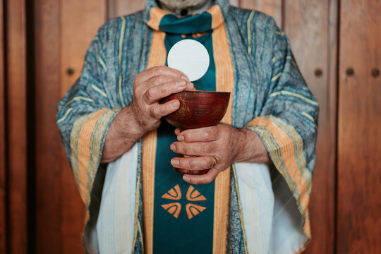 Anonymous priest elevates the Eucharistic host above a chalice, a central ritual in the celebration of the Christian Communion service