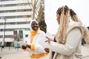 Diverse female friends with documents in urban setting