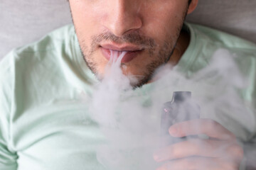 Young man using disposable electronic cigarette