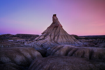 The iconic outline of a badlands rock formation is silhouetted against the mesmerizing colors of a twilight sky, emphasizing its majestic presence