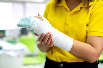 Woman's hand wrapped in white bandage from accident, injury, accident insurance, soft splint on...