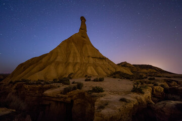 The serene night sky, dotted with countless stars, arches over a solitary badlands spire in a stunning display of natural nocturnal beauty