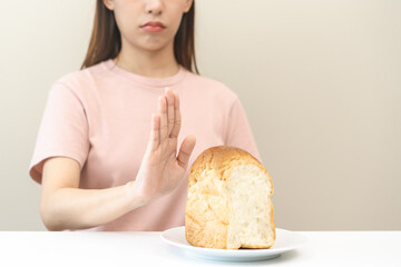 Gluten allergy, asian young woman hand push out, refusing to eat white bread loaf on board in...