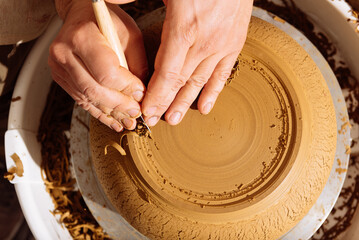 Top view of crop artisan using ribbon tool on clay pot