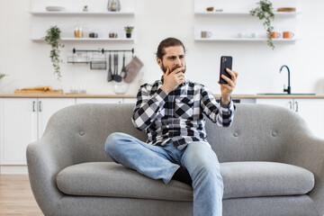 Happy Caucasian person in checkered shirt conducting online conference via modern device sitting on...