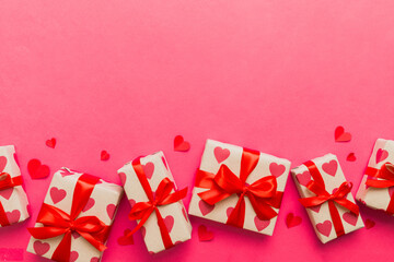 Top view photo of valentine day decorations gift box with red ribbon bow on colored background....
