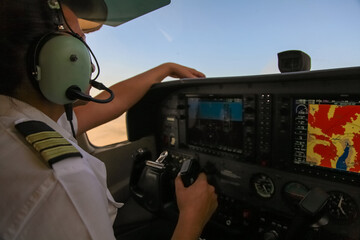 Pilot in uniform with headphones is in cockpit.