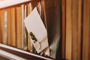 Rustic wedding invitation card mockup, white card with green leaves on the shelf with books
