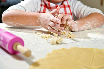 Little girl kneading dough on the table