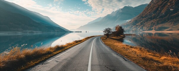 Countryside roadway between mountains and calm lake - obrazy, fototapety, plakaty