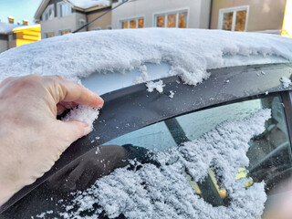 Hand of Woman persons brushing snow of a car window, which frozen over during a bitterly cold morning. Problem with travel and trip in winter