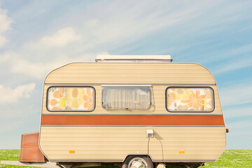 Retro brown striped seventies caravan with flower curtains on a sunny day