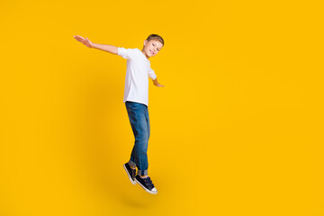 Full length photo of positive funky kid dressed white shirt jumping high flying empty space...