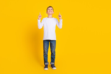 Full length photo of good mood excited boy wear white shirt pointing two fingers up empty space...