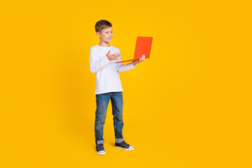 Full length photo of cheerful funny boy wear white shirt communicating modern gadget empty space isolated yellow color background