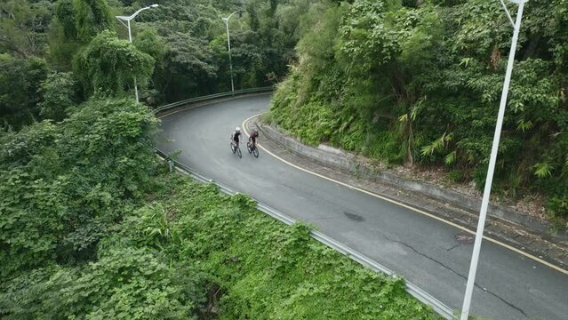 two young asian female cyclists cycling on rural road, drone shot